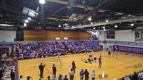 A full gymnasium of 500 students playing a single game of Pong together on the big screen